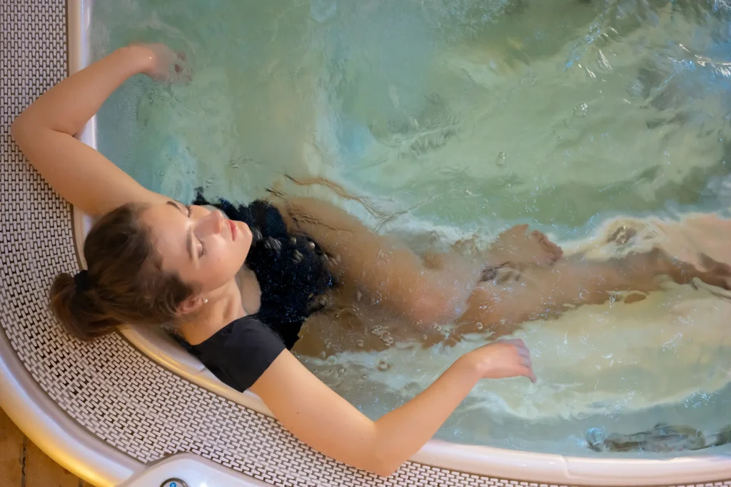 Pictured is an overhead view of a woman soaking in the hot tub at the De' Capuleti Hotel's spa.