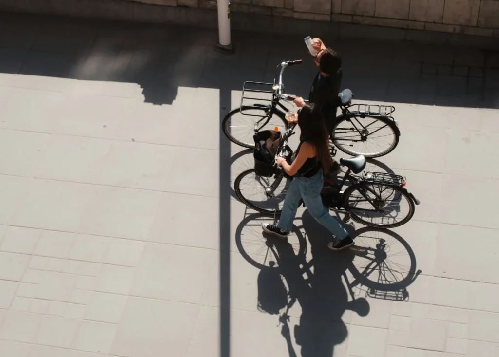 Due persone passeggiano portando a mano due biciclette.